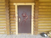 Металлическая дверь с наличниками в бревенчатойикого доме.