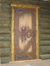 Фото двери в старом стиле из массива с обналичкой из полубревен.